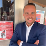 Jerome Reber posant devant l'affiche de sa conférence