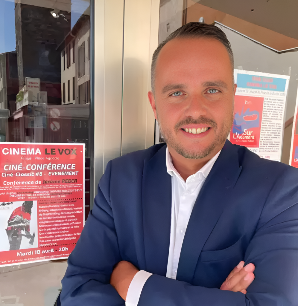 Jerome Reber posant devant l'affiche de sa conférence